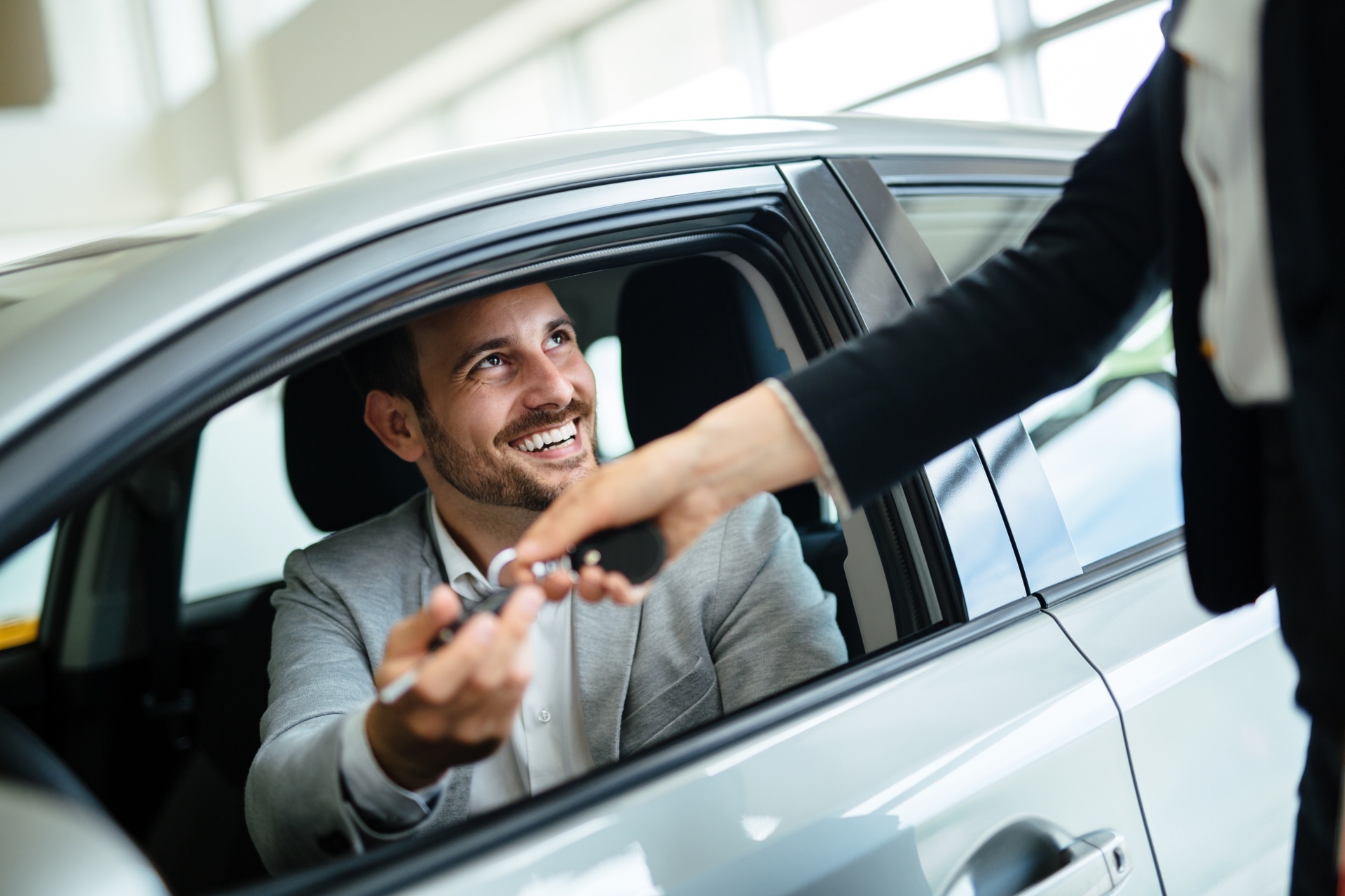 uomo seduto in auto mentre riceve le chiavi dell’auto a noleggio
